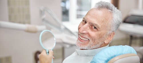 Elderly man smiling while sitting dental chair