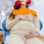 A professional dentist treats and examines the oral cavity of a pregnant girl in a modern dental office. Dentistry.
